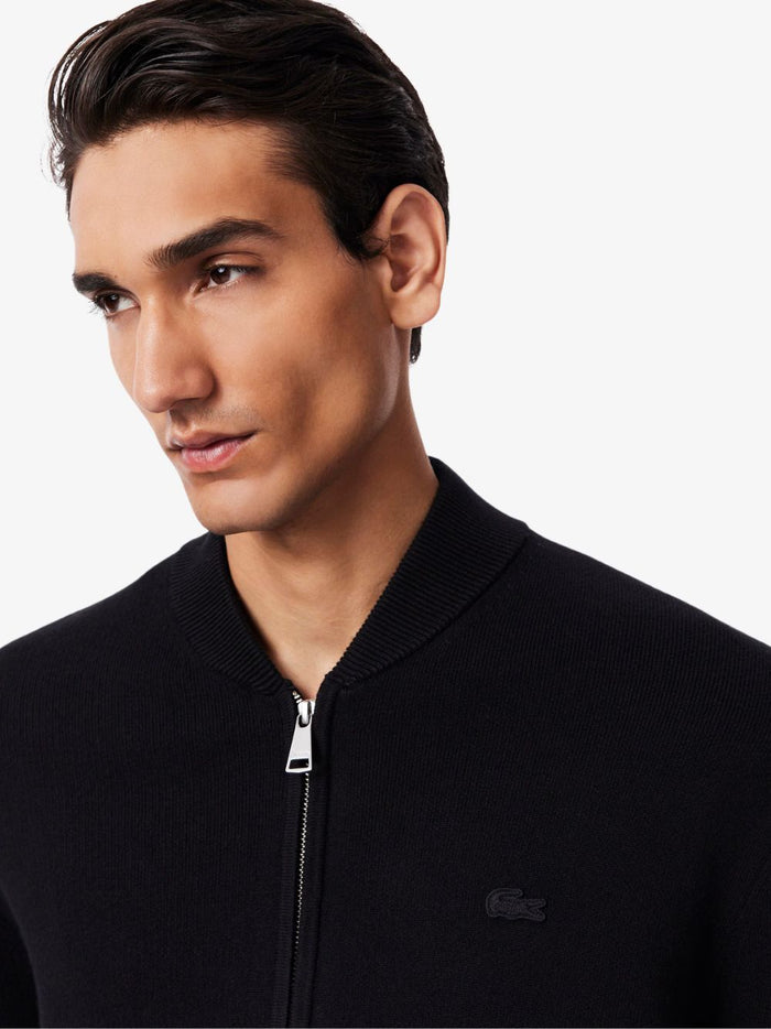 Close-up detail of LACOSTE Black bomber jacket showing cotton and wool knit texture and ribbed collar detail