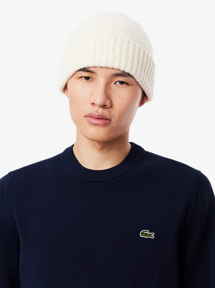 LACOSTE midnight blue cotton sweater close-up detail of crocodile logo embroidery and monochrome fabric texture