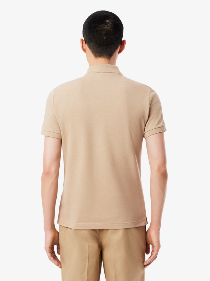 Close-up of LACOSTE polo shirt ribbed collar, mother-of-pearl buttons, and premium piqué fabric weave in beige