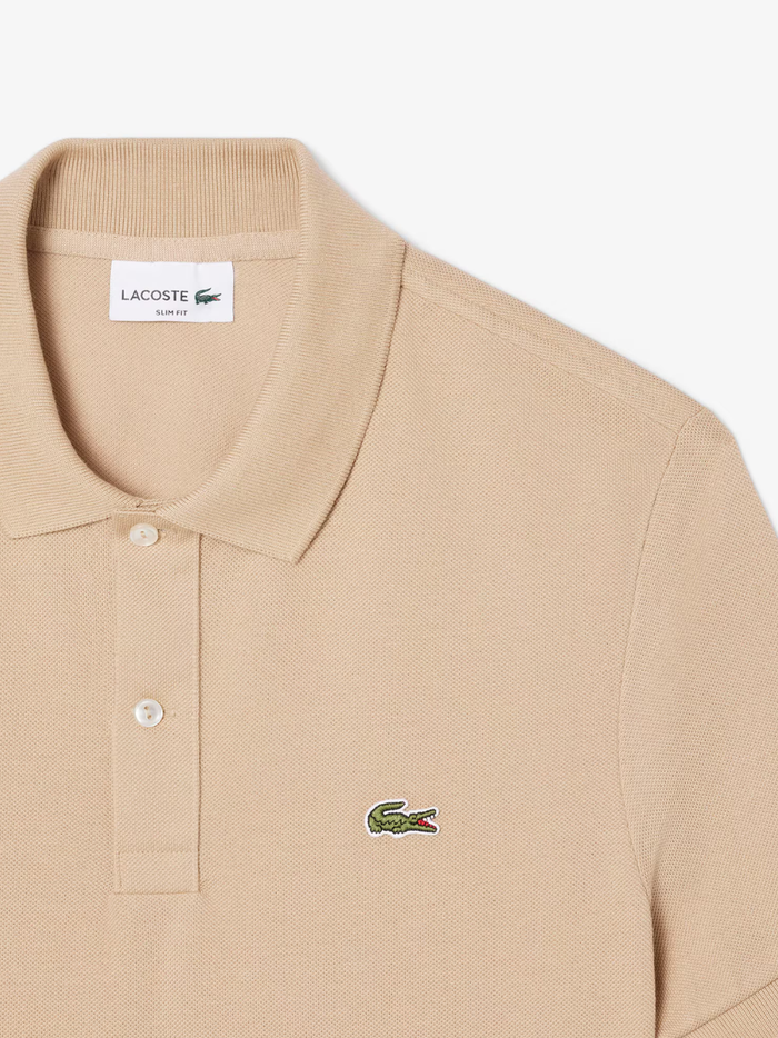 Detail shot of iconic LACOSTE green crocodile embroidery on beige L.12.12 piqué polo shirt chest