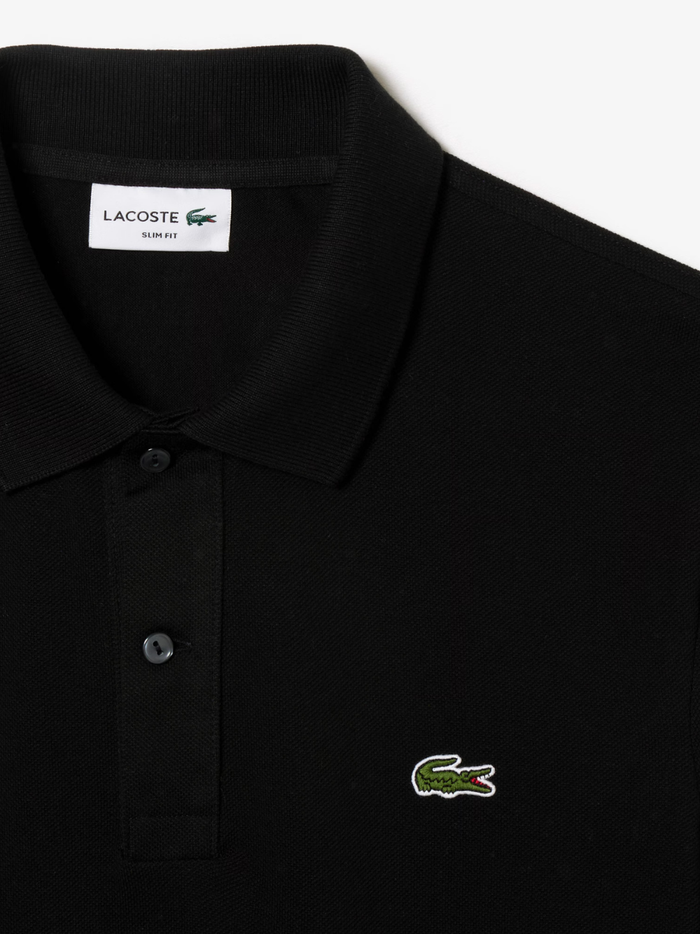 Detail shot of iconic LACOSTE green crocodile embroidery on black L.12.12 piqué polo shirt chest