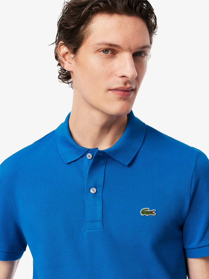 Side profile of LACOSTE L.12.12 denim blue polo shirt highlighting slim fit cut and ribbed collar detail