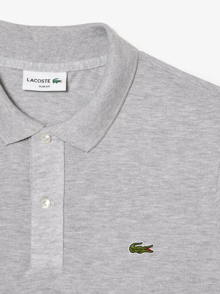 Detail shot of iconic LACOSTE green crocodile embroidery on grey L.12.12 piqué polo shirt chest