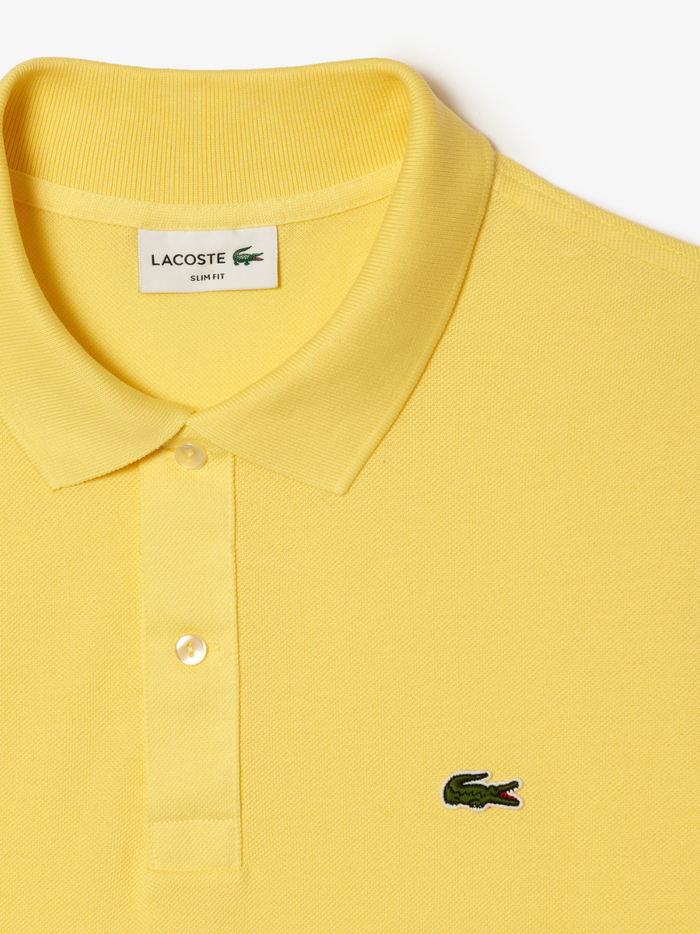Detail shot of iconic LACOSTE green crocodile embroidery on pastel yellow L.12.12 piqué polo shirt chest