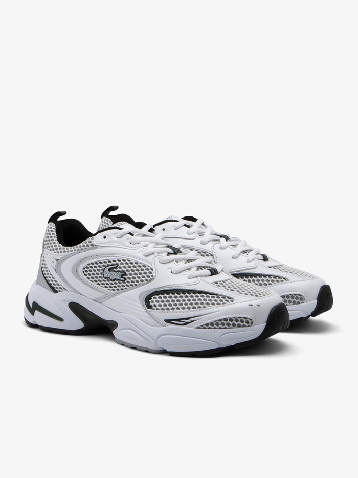 Close-up of LACOSTE Storm 96 2K sneaker heel in white with grey overlays, LACOSTE text branding, and chunky layered midsole