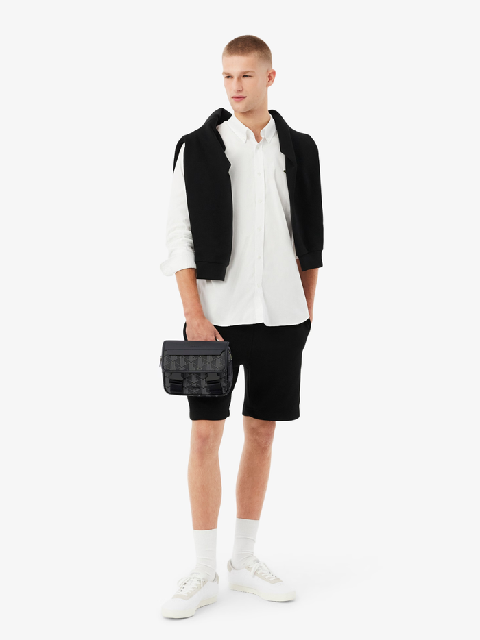 Front view of LACOSTE monogram satchel bag showing clip closure flap and embossed crocodile logo in black and grey