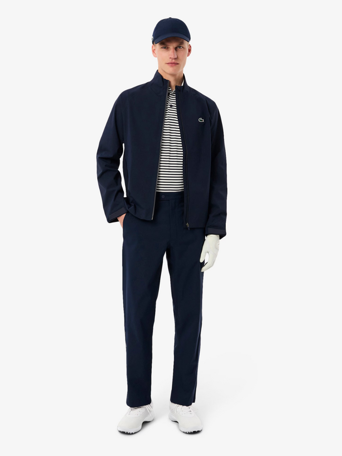 Close-up detail of LACOSTE Water-Repellent Golf Stretch Windbreaker showing navy stretch fabric texture, water-repellent finish and athletic design