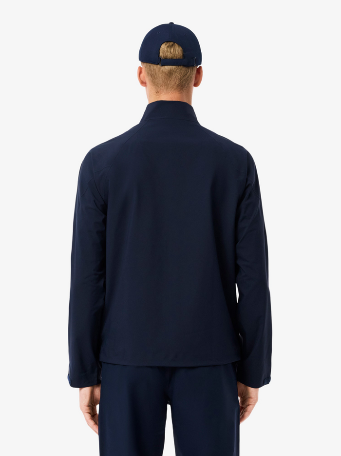 LACOSTE Water-Repellent Golf Stretch Windbreaker chest and collar detail featuring the iconic LACOSTE crocodile logo on navy stretch fabric