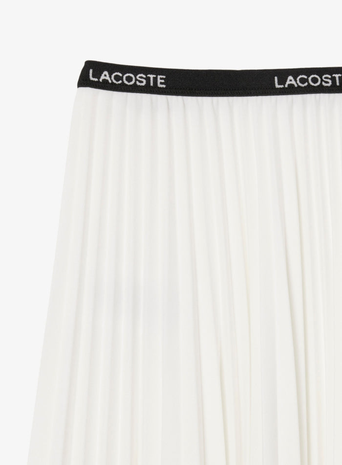 Detail of Lacoste logo waistband on white pleated skirt with contrast branding
